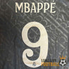 Flocage du nom MBAPPÉ et du numéro 9 sur le dos du maillot Real Madrid 2024, avec fond texturé de lettres entrecroisées